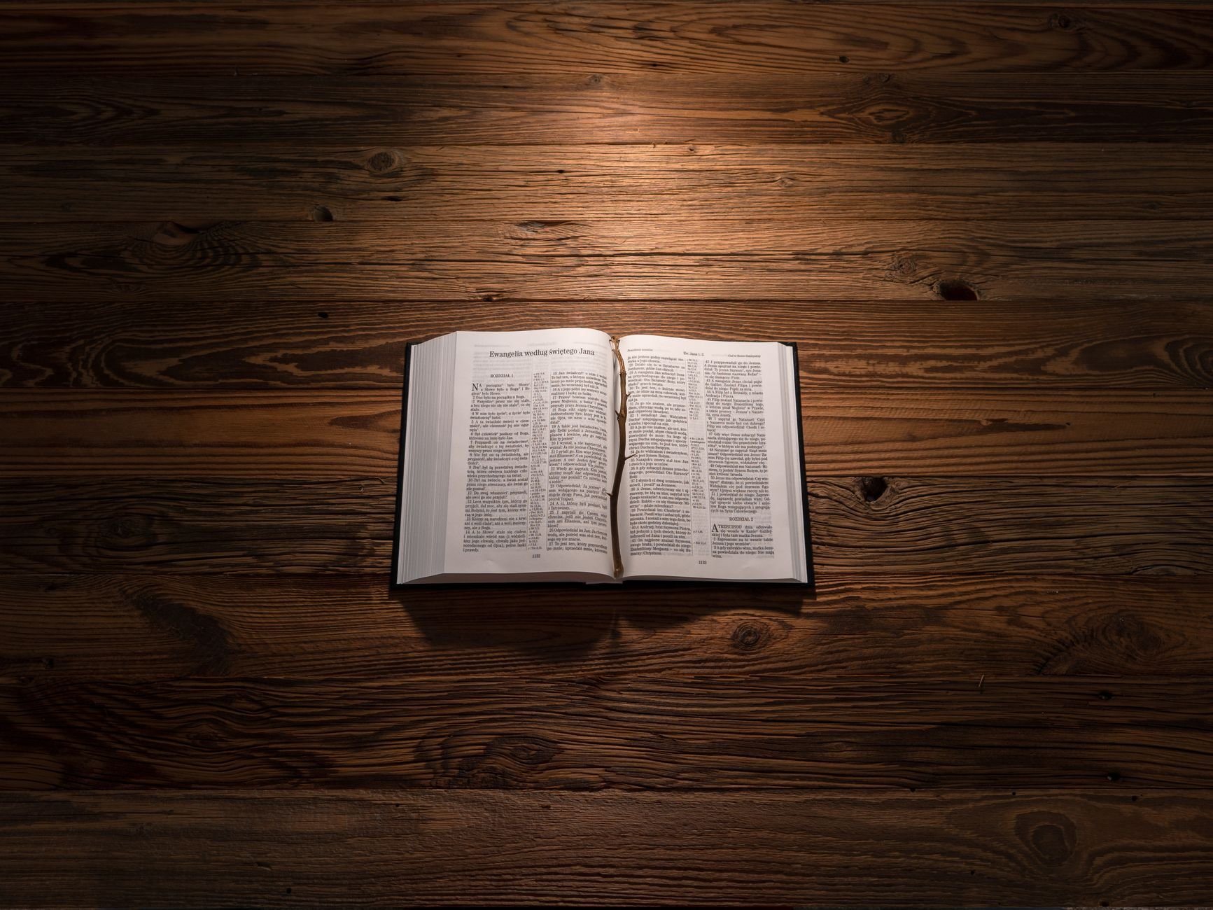An open Bible on a wooden table, softly lit, symbolizing reflection and spirituality